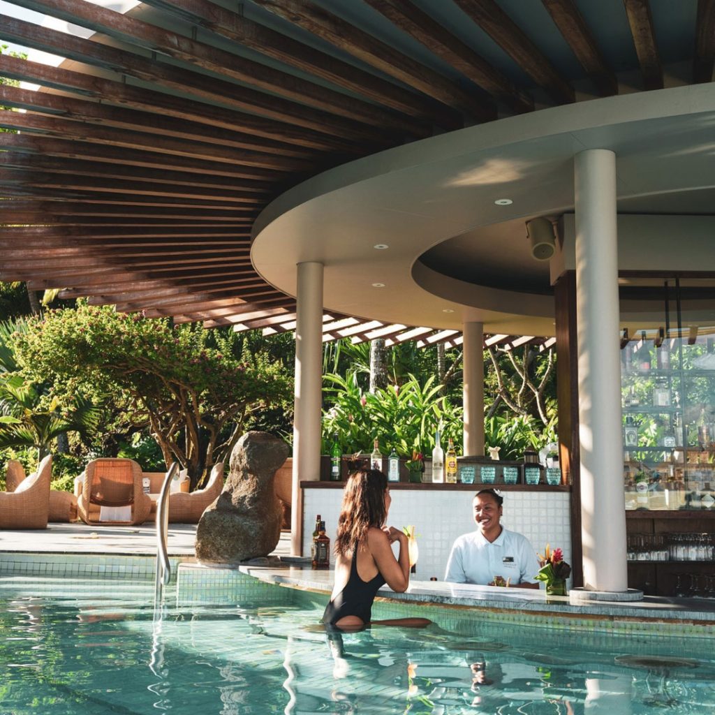 | Blue Tahiti Travel Arava Pool Bar at Conrad Bora Bora Nui, Featuring a Swim-up Bar, Overwater Cabanas, and Panoramic Views of the Turquoise Lagoon and Mount Otemanu.