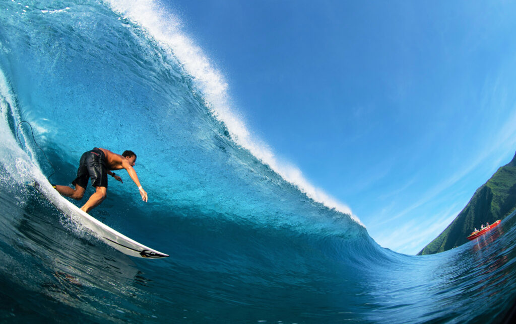 | Blue Tahiti Travel a Surfer Riding the Waves in Tahiti, Experiencing One of the Most Exhilarating Tahiti Activities in the World Renowned Surf Spots of the Islands.